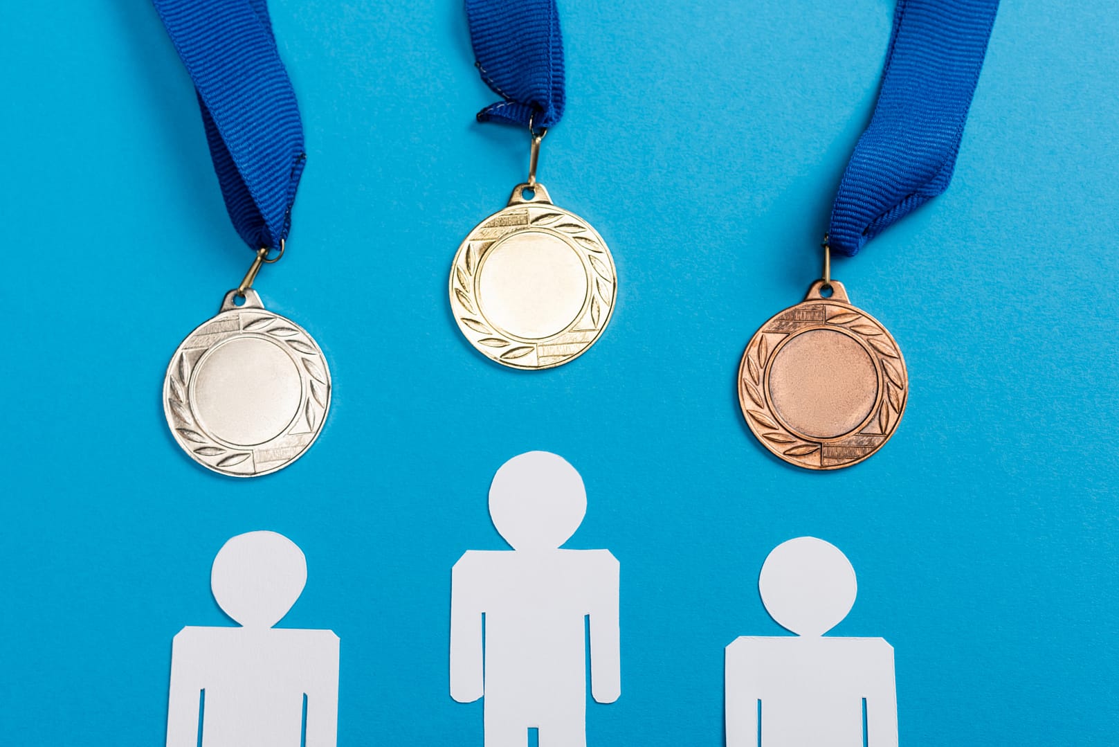 top view of white paper cut people near medals on blue